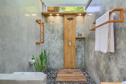 a bathroom with a shower with a wooden door at Romantic Barn with Mt. Agung Views in Sidemen