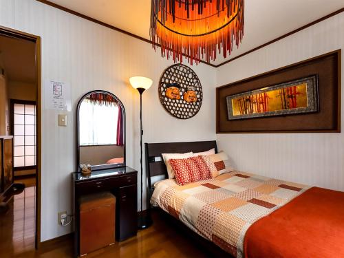 a bedroom with a bed and a table and chandelier at Maguro House in Osaka