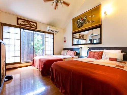 a bedroom with two beds and a couch and windows at Maguro House in Osaka