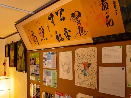 a wall with drawings and posters on it at Maguro House in Osaka