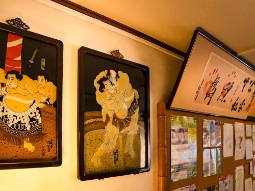 a group of framed pictures hanging on a wall at Maguro House in Osaka