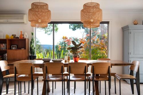 a dining room with a wooden table and chairs at Cornish Hill House - stunning views with pool in Daylesford