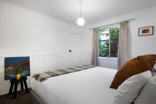 a bedroom with a white bed and a window at Cornish Hill House - stunning views with pool in Daylesford