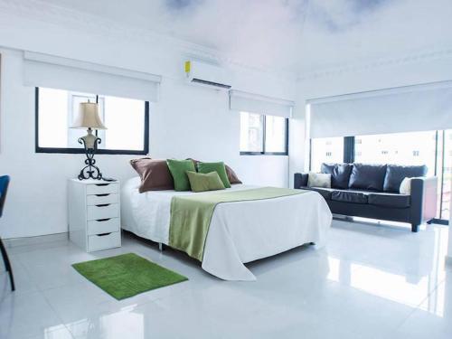 ein weißes Schlafzimmer mit einem großen Bett und einem Sofa in der Unterkunft Malecon Cozy - Premium Plus 13 in Santo Domingo