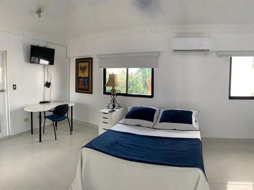 ein weißes Schlafzimmer mit einem Bett und einem Tisch in der Unterkunft Room in Condo - Malecon Premium Rooms in Santo Domingo
