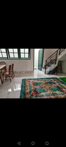 a room with a large rug and a table and chairs at ZG Homy Jogja in Gondowulung