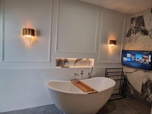 a white bath tub in a bathroom with a tv at RESIDENTIAL 4 BEDROOM House in Coffs Harbour