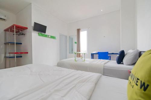 a white room with two beds and a tv at Urbanview Hotel Ephe Palembang by RedDoorz in Palembang