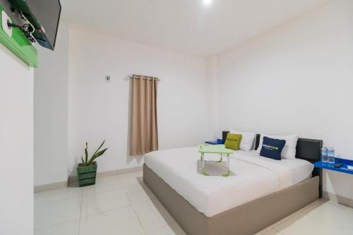 a white room with a bed and a tv at Urbanview Hotel Ephe Palembang by RedDoorz in Palembang