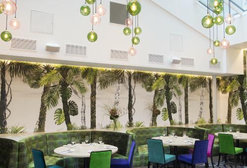 a restaurant with tables and chairs and palm trees at Thon Hotel Rosenkrantz Oslo in Oslo