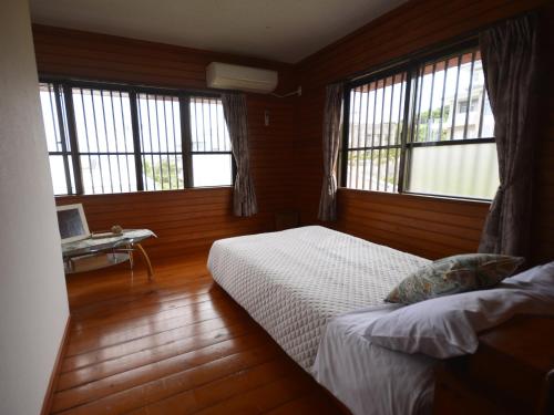 a bedroom with a bed and a desk and windows at Buzz Resort in Onna
