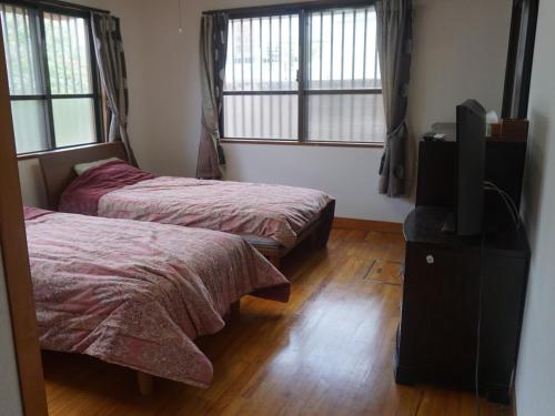 a bedroom with two beds and a flat screen tv at Buzz Resort in Onna