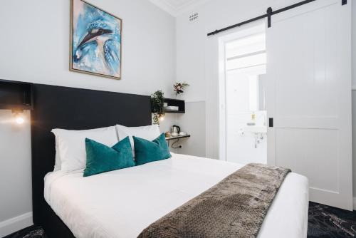a bedroom with a large white bed with blue pillows at Royal Hotel Wyong in Wyong