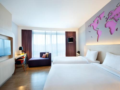 a hotel room with two beds and a room with a world on the wall at Ibis Styles Jakarta Airport in Tangerang