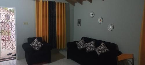 a living room with two chairs and a window at Oak Villa Montego Bay 2 in Montego Bay