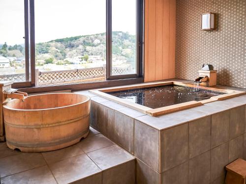 a large bath tub in a room with a window at Kameyama Onsen Hotel in Kimitsu