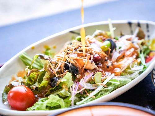 a salad in a white bowl with dressing on it at Kameyama Onsen Hotel in Kimitsu