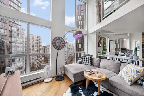 a living room with a couch and a large window at Rare Find Loft with full kitchen at Heart of Downtown in Vancouver