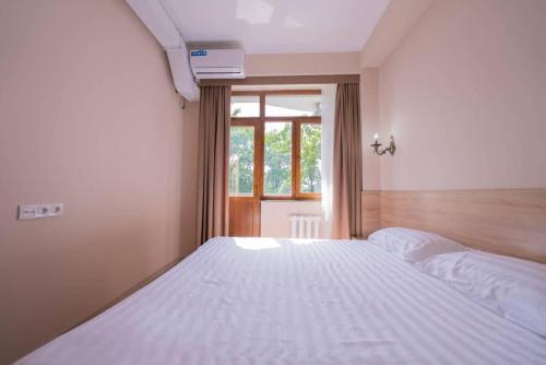 a bedroom with a large white bed with a window at Kaganat Hostel in Bishkek