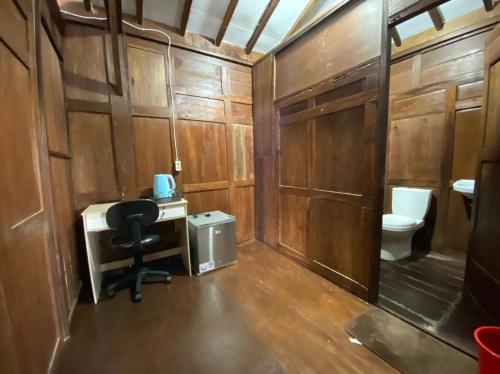 a bathroom with a toilet and a desk and a chair at Baron Hill Resort Gunung Kidul Mitra RedDoorz in Baron