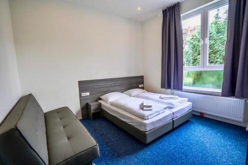 a bedroom with a bed and a couch and a window at Hotel City Meetpoint in Hamburg