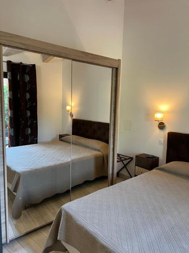 a bedroom with two beds and a mirror at Pleasant private villa Located in a garden of 8000m2 with trees in Porto-Vecchio