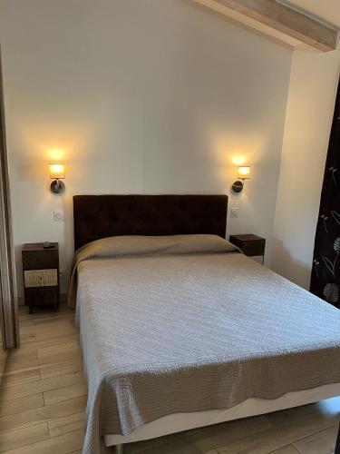 a bedroom with a bed with two lights on the wall at Pleasant private villa Located in a garden of 8000m2 with trees in Porto-Vecchio