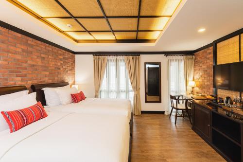 a bedroom with a white bed and a brick wall at El Barrio Lanna in Chiang Mai