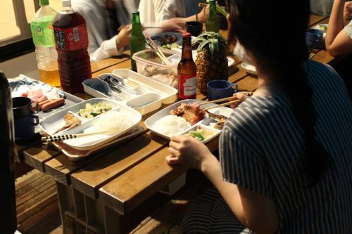 a woman sitting at a table with food and drinks at Sun Floralは古宇利島まで3分で完全プライベート1棟貸 in Nago