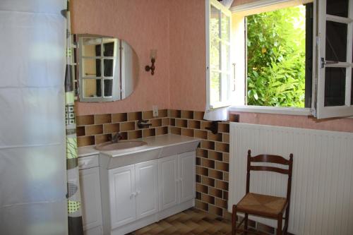 a bathroom with a sink and a mirror and a chair at Holiday home Maison de la litiére in Pugny-Chatenod