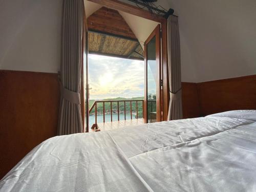 a bedroom with a bed and a view of the ocean at Baron Hill Resort Gunung Kidul Mitra RedDoorz in Baron