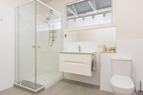 a white bathroom with a shower and a toilet at The Ritz in Yamba