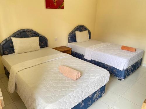 a room with two beds with white sheets at Twins Homestay in Canggu