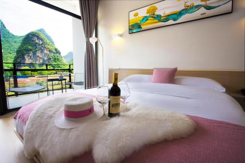 a bed with a bottle of wine and a hat on it at Sure I Do全景山宿 in Yangshuo