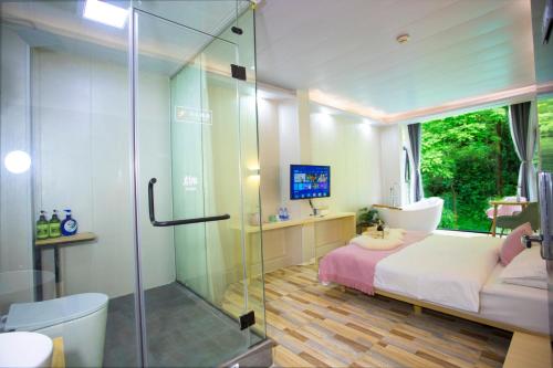 a bathroom with a glass shower and a bed and a toilet at Sure I Do全景山宿 in Yangshuo