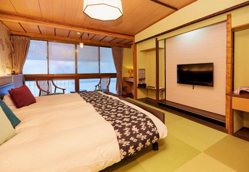 a bedroom with a bed and a flat screen tv at Hanakanzashi in Nihommatsu