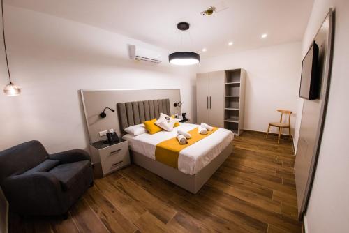 a bedroom with a bed and a chair and a television at City Stay B&B in Taʼ l-Imgħajjen