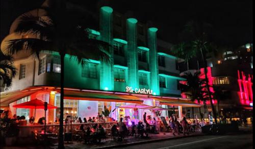 a group of people standing outside of a building at night at The Carlyle Oceanfront Luxe Condo Miami Beach in Miami Beach