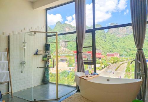 a bathroom with a tub and a large window at Sure I Do全景山宿 in Yangshuo