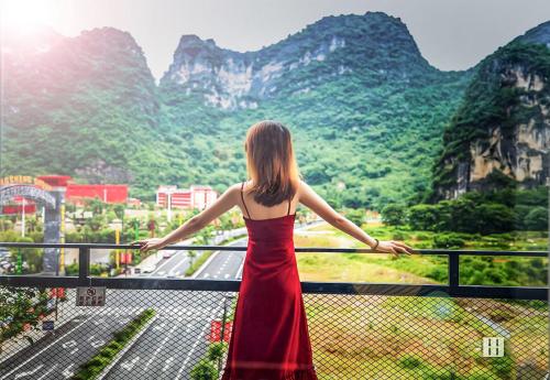 a woman standing on a balcony looking at the mountains at Sure I Do全景山宿 in Yangshuo