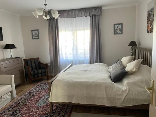 a bedroom with a bed and a chair and a window at Csalogány Vendégház in Szerencs