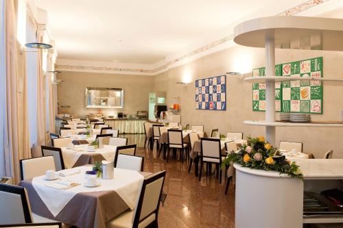 a dining room with white tables and chairs and a restaurant at Hotel San Pietro in Verona