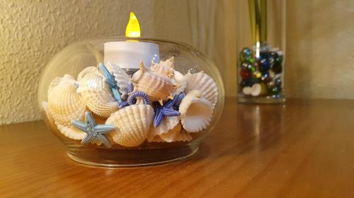 a glass bowl filled with shells and a candle on a table at Piso familiar con amplia terraza 300m de la playa in Cullera