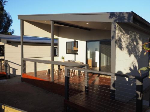 a house with a deck with a table and chairs at Ardrossan Caravan Park in Ardrossan