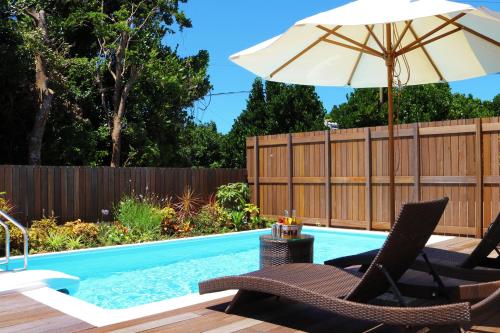 a swimming pool with two chairs and an umbrella at Villa Piscine SESOKO -SEVEN Hotels and Resorts- in Motobu