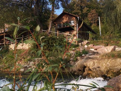 a log cabin next to a river with a waterfall at Rooms S&I Korana in Slunj