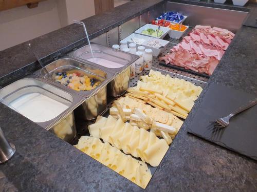 a buffet with cheese and other foods on a counter at Hotel Garni Romantik in Fügen