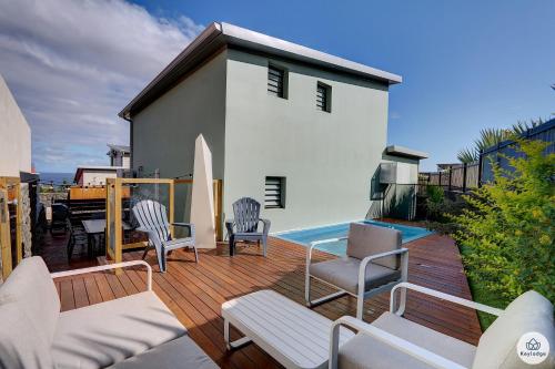 une terrasse avec des chaises, une piscine et une maison dans l'établissement Villa du Toucan Bleu - 4 étoiles - Piscine - Lagon de Saint-Leu, à Saint-Leu