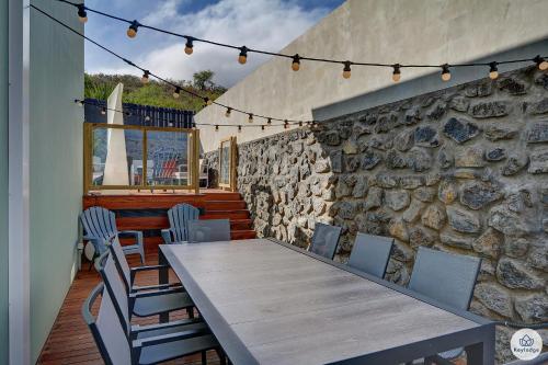 une table et des chaises sur une terrasse avec un mur en pierre dans l'établissement Villa du Toucan Bleu - 4 étoiles - Piscine - Lagon de Saint-Leu, à Saint-Leu