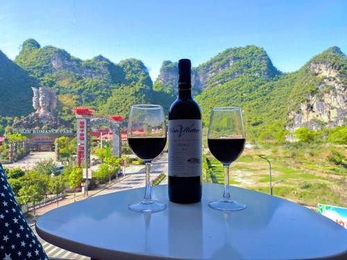 a bottle of wine and two glasses on a table at Sure I Do全景山宿 in Yangshuo